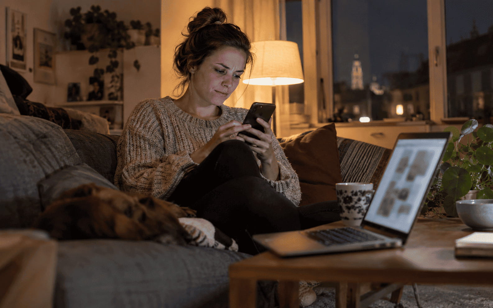 Symbolbild: Frau sucht abends auf dem Sofa per Smartphone nach Jobs